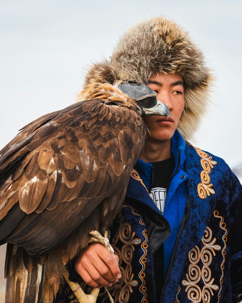 A man and his eagle look stoically ahead.
